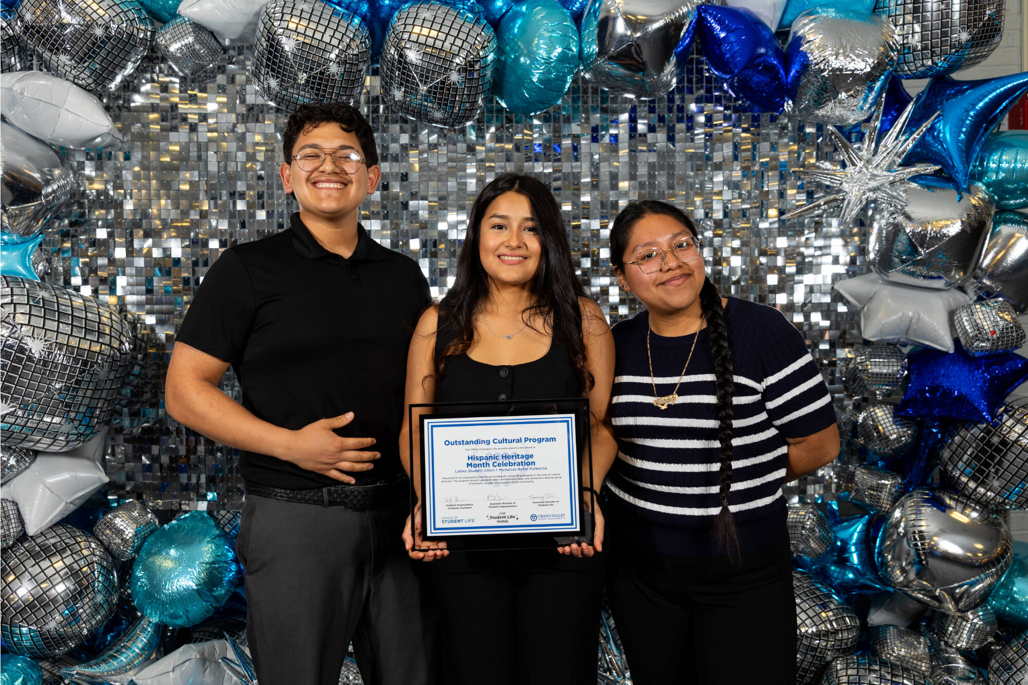 Three individuals holding an award certificate